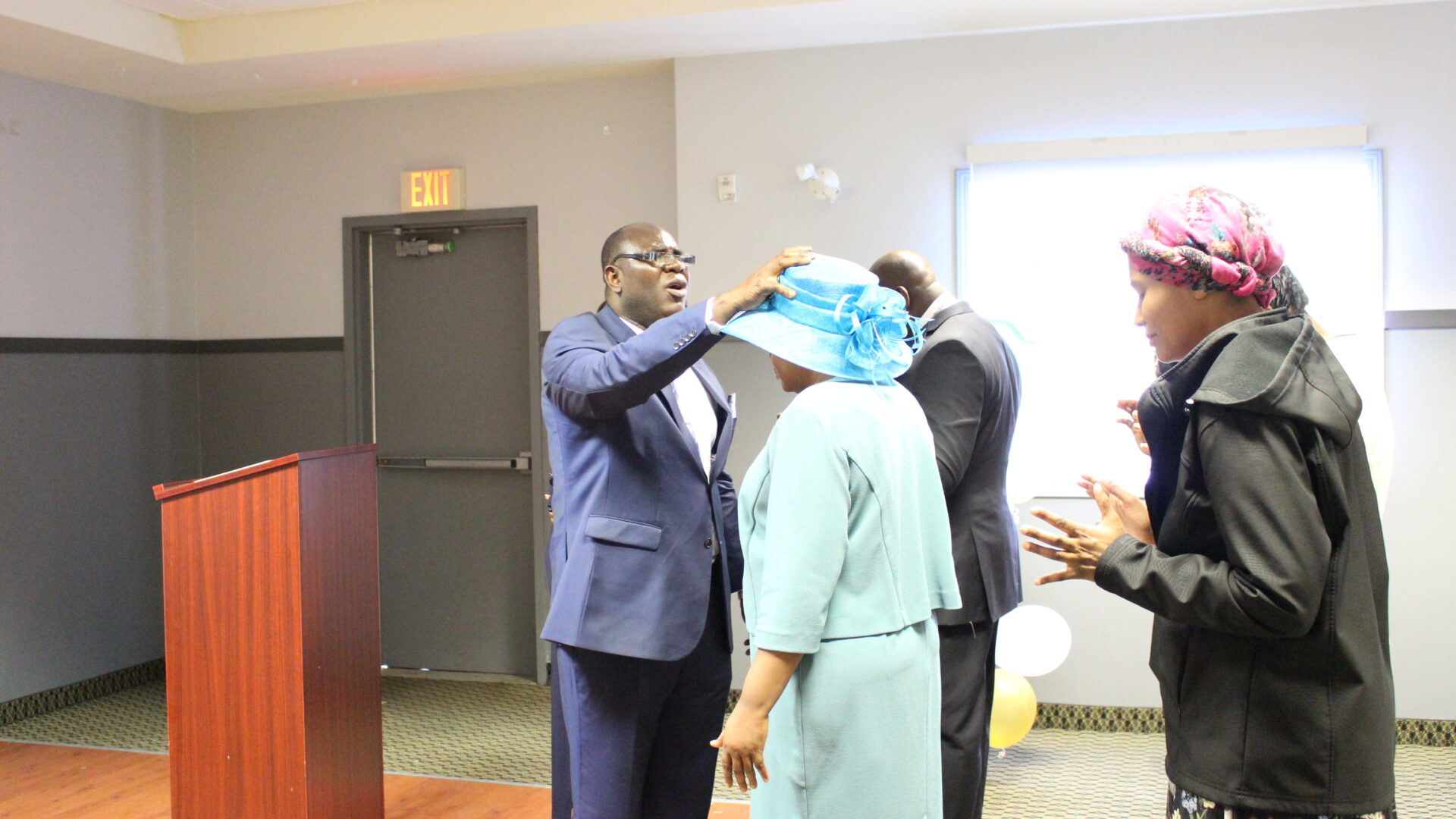 A pastor placing his hand on a person’s hat while praying
